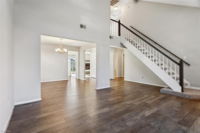 unfurnished living room featuring dark wood-type flooring, high vaulted ceiling, and a chandelier