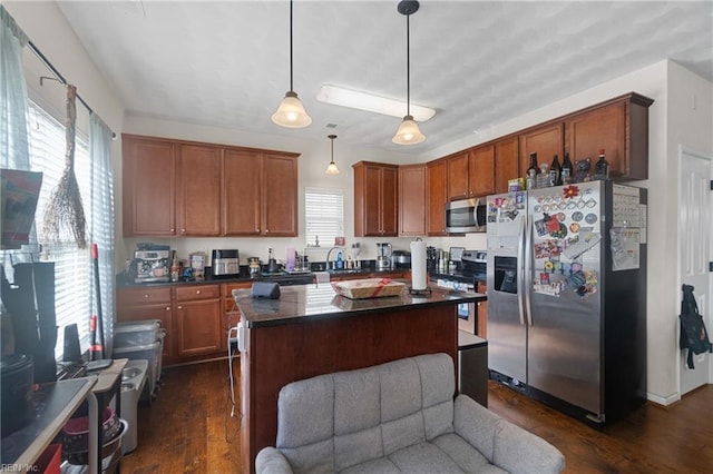 kitchen with pendant lighting, dark hardwood / wood-style floors, a center island, and appliances with stainless steel finishes