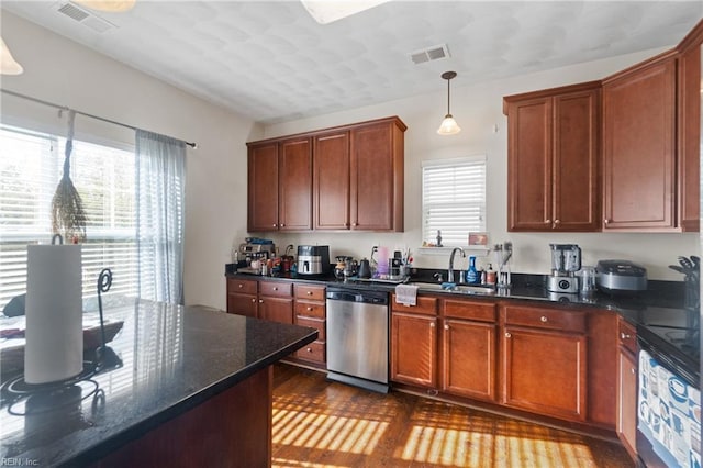 kitchen featuring stainless steel dishwasher, a wealth of natural light, sink, dark stone countertops, and hanging light fixtures