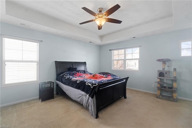 carpeted bedroom featuring ceiling fan and a tray ceiling