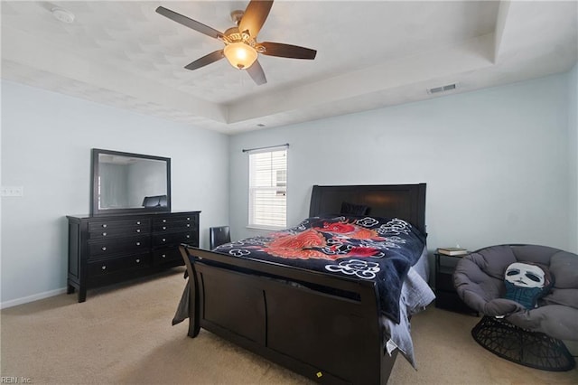 carpeted bedroom with a raised ceiling and ceiling fan