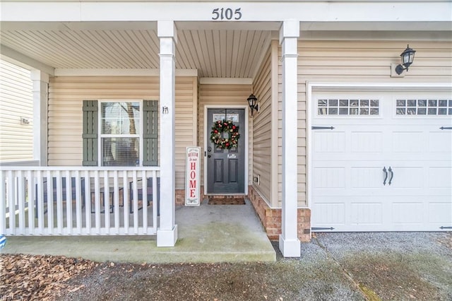 doorway to property featuring covered porch and a garage