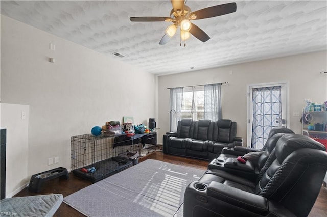 living room featuring dark hardwood / wood-style floors, ceiling fan, and a textured ceiling