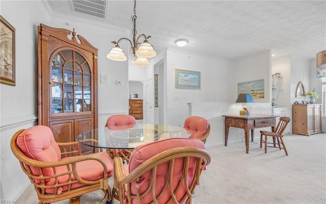 carpeted dining area with a chandelier and ornamental molding