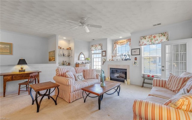 carpeted living room with built in shelves, a textured ceiling, ceiling fan, and crown molding