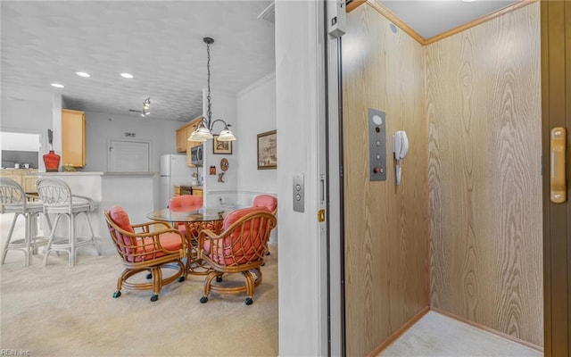 dining area featuring wooden walls, light colored carpet, ornamental molding, and elevator