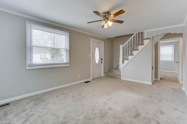 carpeted entryway with ceiling fan and crown molding