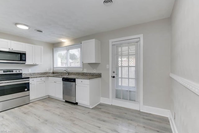 kitchen with white cabinets, sink, light wood-type flooring, and stainless steel appliances