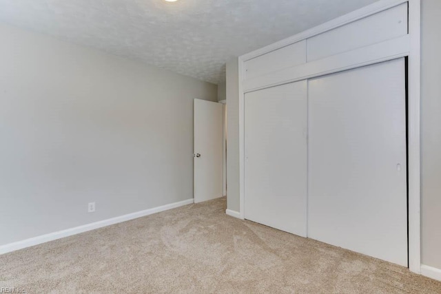 unfurnished bedroom featuring a closet, light colored carpet, and a textured ceiling