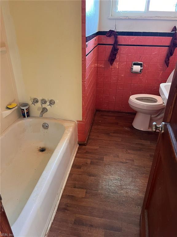 bathroom featuring wood-type flooring, tile walls, and toilet