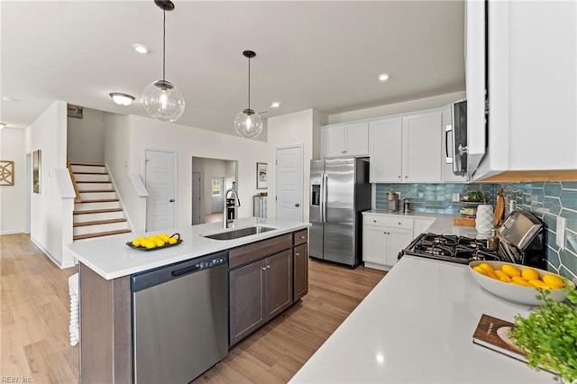 kitchen with sink, white cabinets, stainless steel appliances, and a center island with sink