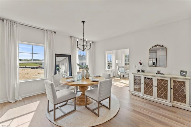 dining space with light hardwood / wood-style flooring and a notable chandelier