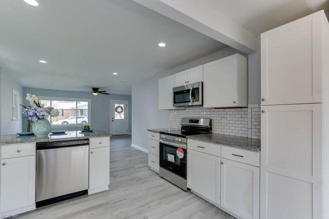 kitchen featuring white cabinets, ceiling fan, decorative backsplash, light wood-type flooring, and appliances with stainless steel finishes