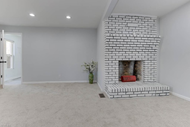 unfurnished living room with light carpet and a brick fireplace