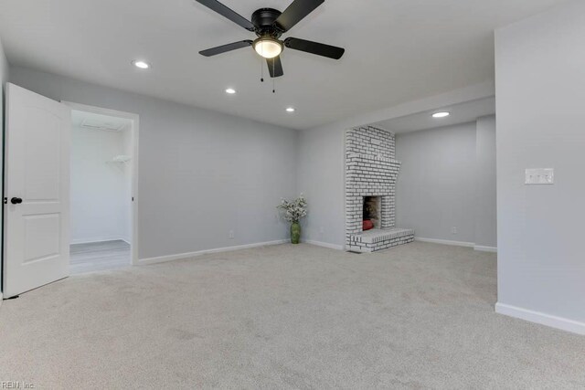 unfurnished living room featuring ceiling fan, light carpet, and a brick fireplace