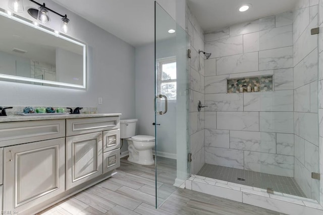 bathroom with vanity, toilet, and a shower with door