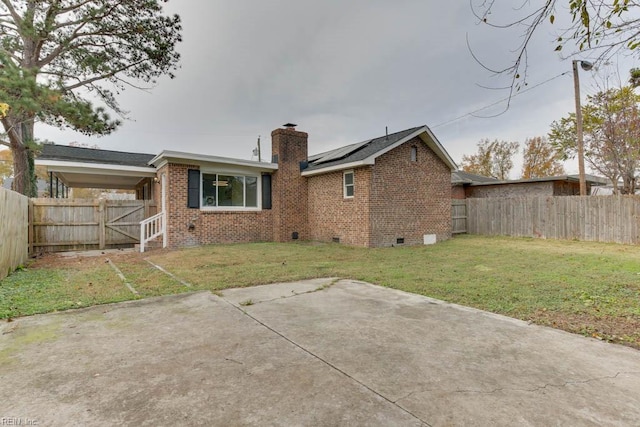 rear view of house with a lawn and solar panels