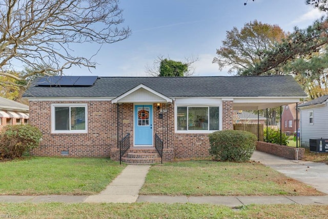 view of front of house featuring central AC, a front yard, and solar panels