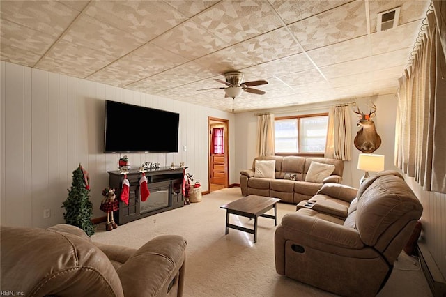 carpeted living room with ceiling fan and wooden walls