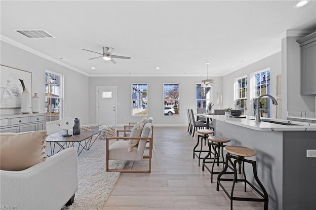 living room with crown molding, sink, ceiling fan, and light hardwood / wood-style flooring