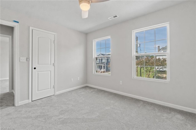 unfurnished room with a wealth of natural light, ceiling fan, and light carpet