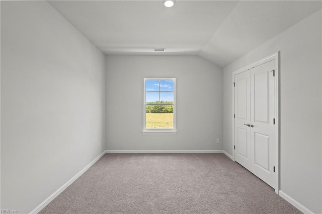 unfurnished bedroom featuring light colored carpet and vaulted ceiling