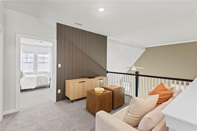 living area featuring ceiling fan, light carpet, and wooden walls