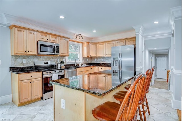 kitchen with light brown cabinetry, sink, a center island, and appliances with stainless steel finishes