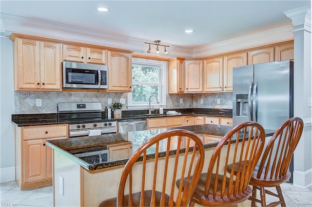 kitchen with appliances with stainless steel finishes, a center island, light tile patterned floors, and dark stone countertops