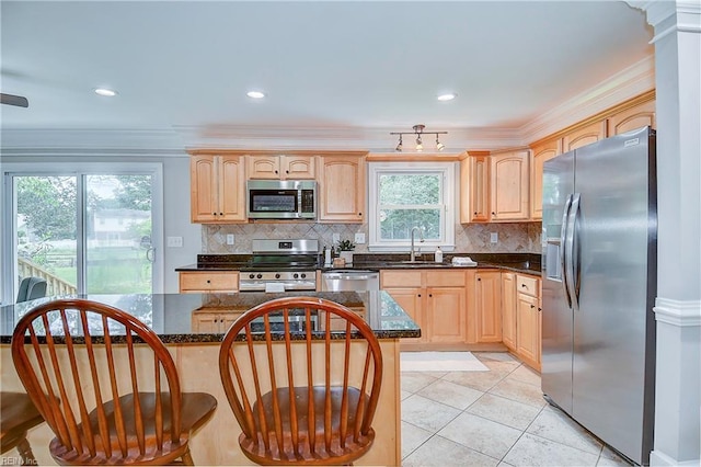 kitchen featuring sink, crown molding, dark stone counters, light tile patterned flooring, and appliances with stainless steel finishes