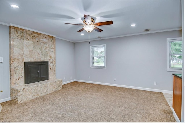 unfurnished living room featuring ceiling fan, crown molding, a fireplace, and light carpet