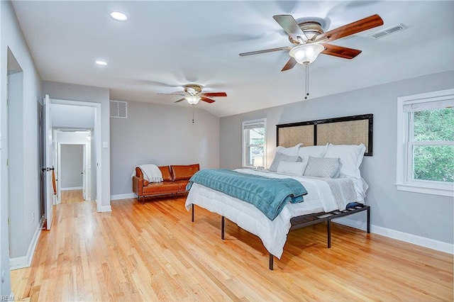 bedroom with ceiling fan, vaulted ceiling, light wood-type flooring, and multiple windows