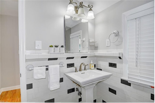 bathroom with a chandelier, wood-type flooring, and tile walls