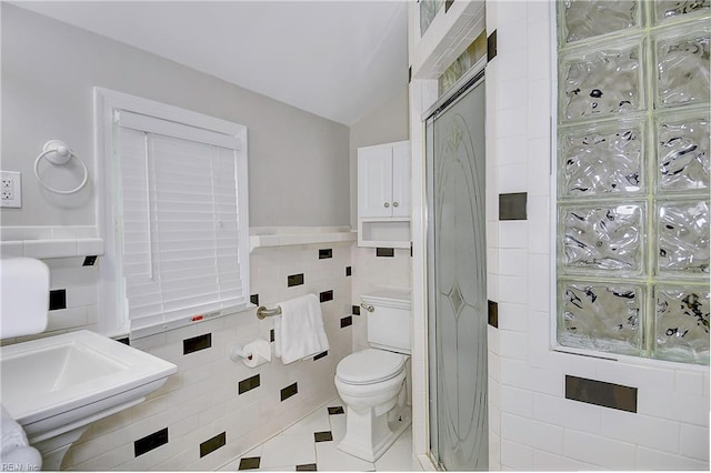 bathroom with lofted ceiling, sink, tile patterned flooring, toilet, and tile walls