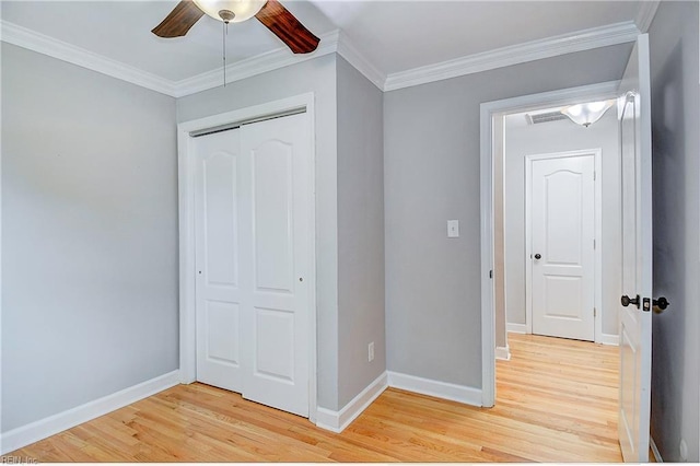 unfurnished bedroom featuring a closet, light hardwood / wood-style flooring, ceiling fan, and crown molding