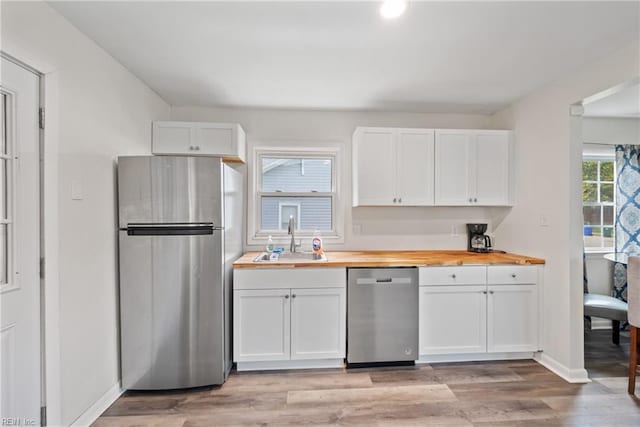 kitchen featuring white cabinetry, butcher block counters, sink, stainless steel appliances, and light hardwood / wood-style flooring