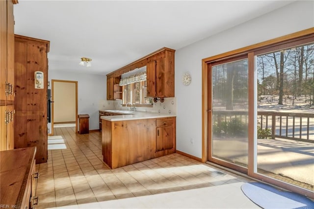 kitchen with decorative backsplash, kitchen peninsula, and sink