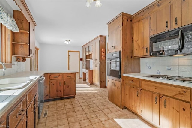 kitchen featuring backsplash, tile countertops, sink, stainless steel appliances, and light tile patterned floors