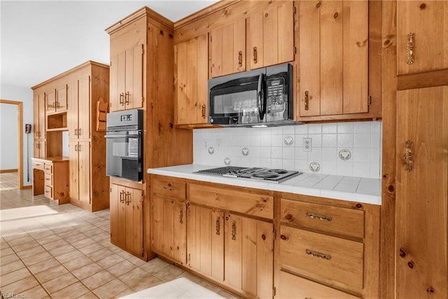 kitchen featuring light tile patterned flooring, tile countertops, decorative backsplash, and black appliances