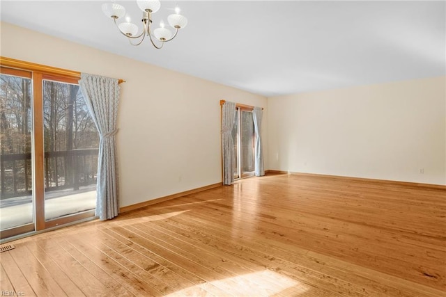 unfurnished room featuring a chandelier and light hardwood / wood-style flooring