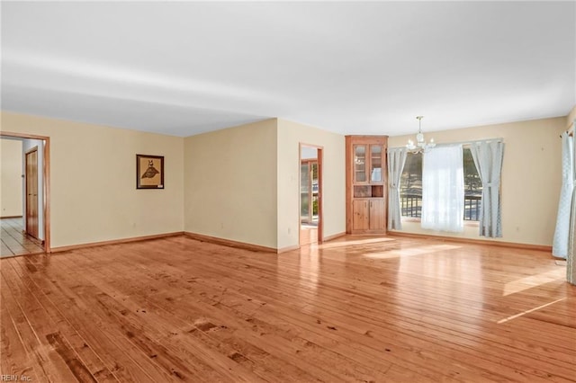 unfurnished living room featuring light hardwood / wood-style flooring and an inviting chandelier