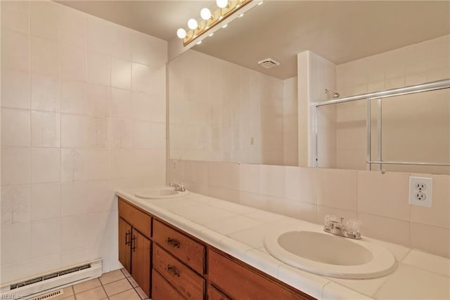 bathroom with baseboard heating, tile patterned flooring, tile walls, an enclosed shower, and vanity