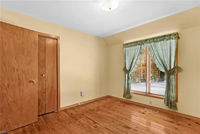 empty room featuring lofted ceiling and wood-type flooring