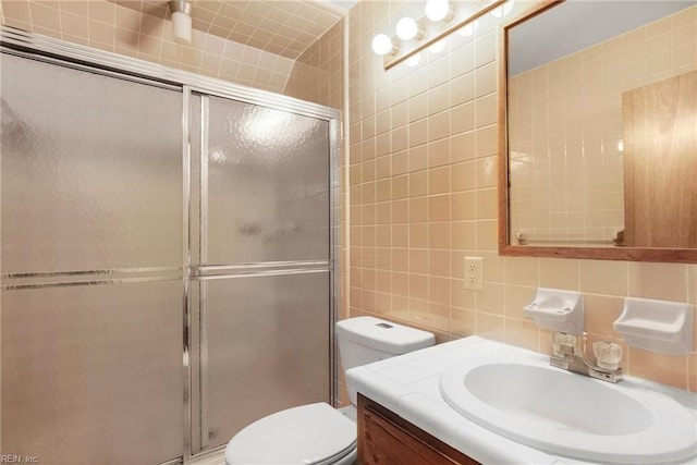 bathroom with an enclosed shower, vanity, decorative backsplash, tile walls, and toilet