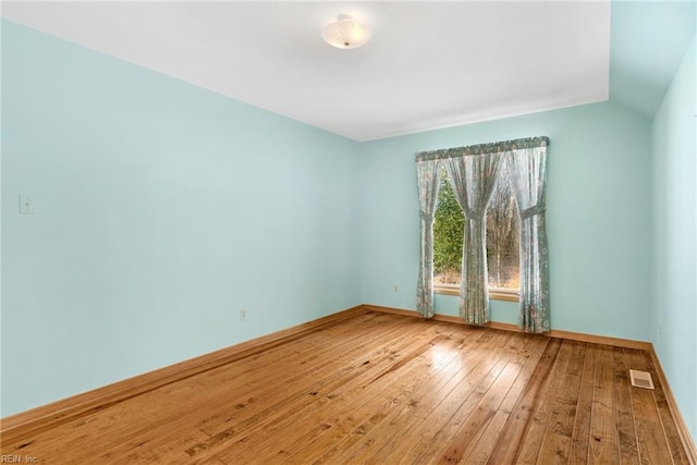 empty room featuring vaulted ceiling and hardwood / wood-style floors