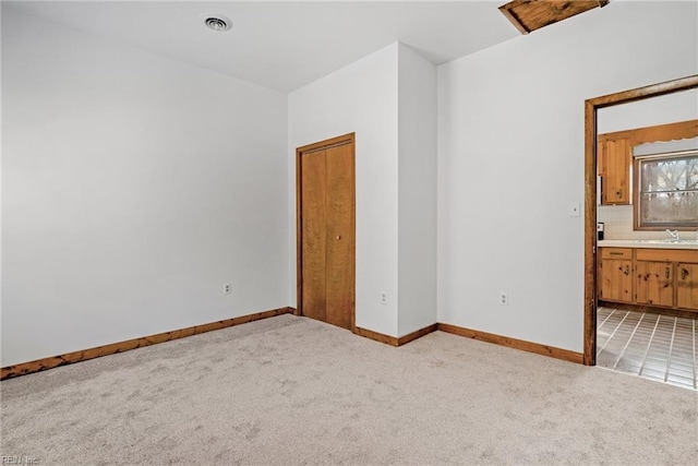 unfurnished room featuring light carpet and sink