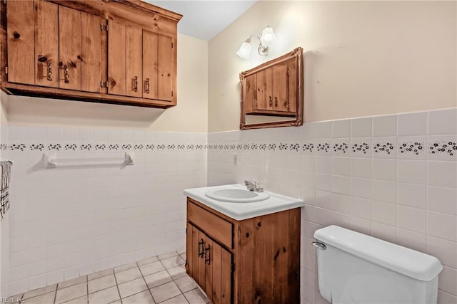 bathroom with toilet, vanity, tile walls, and tile patterned floors