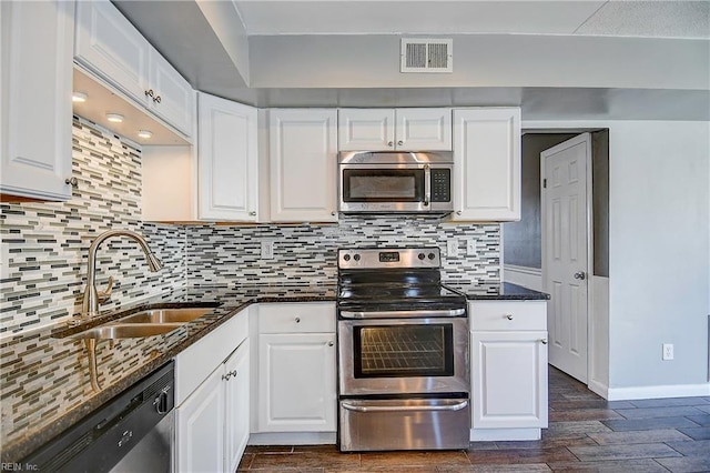 kitchen with decorative backsplash, white cabinetry, sink, and appliances with stainless steel finishes