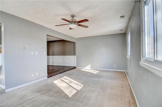 carpeted empty room featuring ceiling fan and a textured ceiling