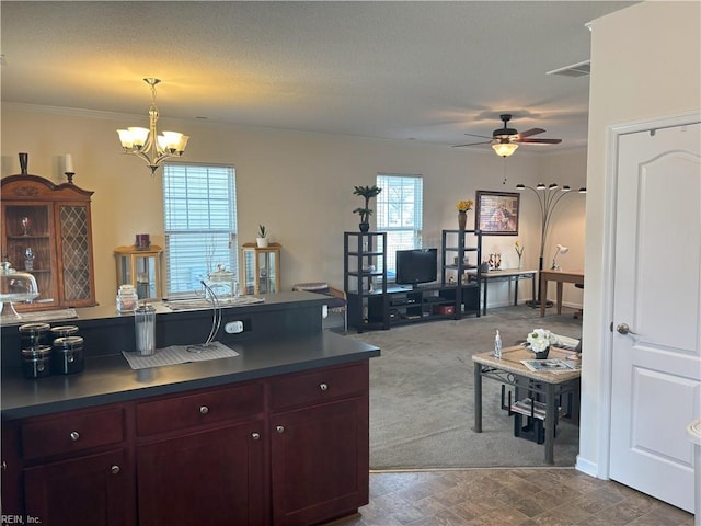 kitchen featuring pendant lighting, ceiling fan with notable chandelier, ornamental molding, and dark colored carpet